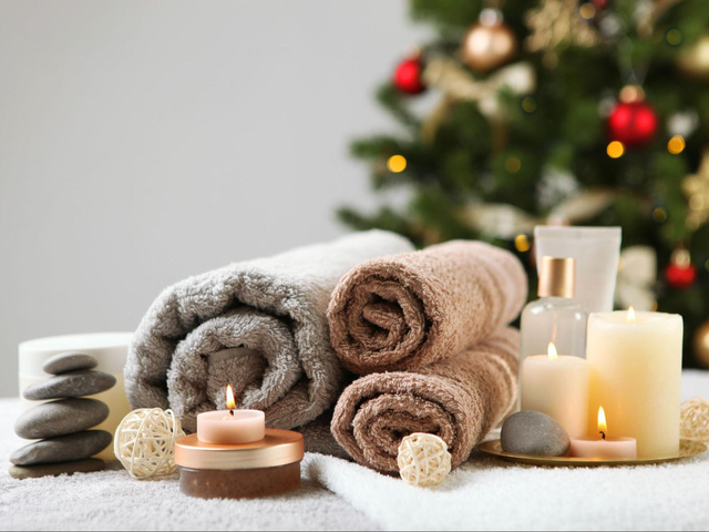 Rolled spa towels, warm stones and candles ready for Christmas spa package in front of a Christmas tree at Earth and Skin day spa